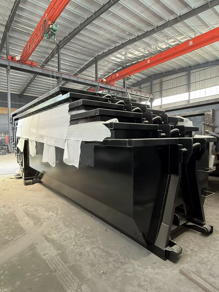 Black tub-style roll-off containers in a fabrication facility
